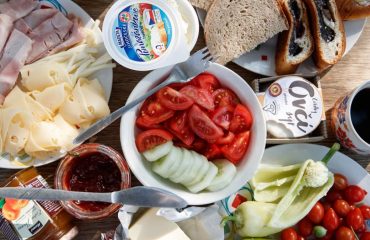 Delicious breakfast setup with cheese, cold cuts, bread, and fresh vegetables.